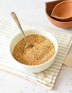 a white bowl filled with oatmeal next to a wooden spoon on top of a table