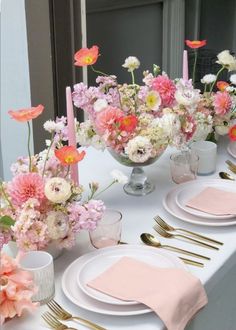 the table is set with pink and white flowers in vases, silverware, and napkins