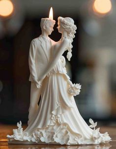 a wedding cake topper with a candle in the shape of a bride and groom