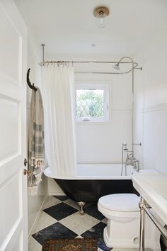 a black and white checkered floor in a bathroom with a tub, toilet and shower curtain