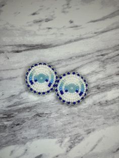 two blue and white beaded earrings sitting on top of a marble surface with an oval design