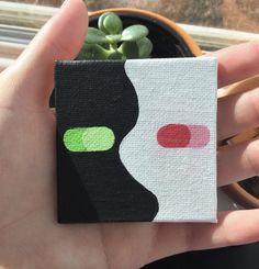 a hand holding a small square piece of paper with circles on it and a succulent plant in the background