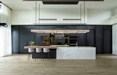 an open kitchen and dining area with wood floors, black walls and white countertops