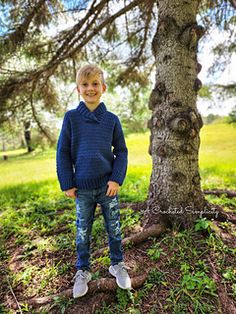 a young boy standing in front of a tree