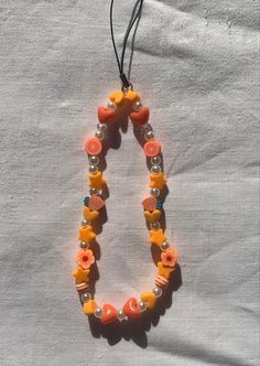 an orange and white beaded necklace hanging from a string on top of a table