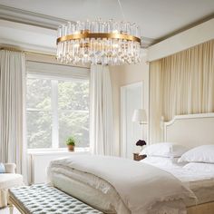 a bedroom with a large bed and a chandelier hanging from it's ceiling