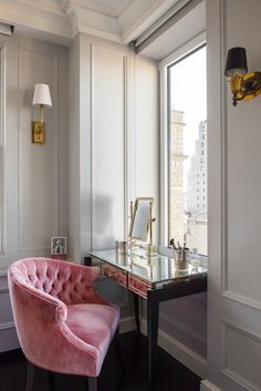 a pink velvet chair sitting in front of a desk