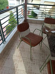 two brown chairs sitting on top of a balcony