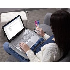 a woman is sitting on the couch with her laptop and cell phone in front of her