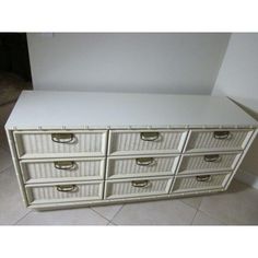 a white dresser with wicker drawers and gold handles