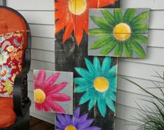 some colorful flowers painted on wood are sitting next to a chair and potted plant