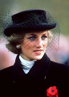 a woman wearing a black hat with a birdcage veil