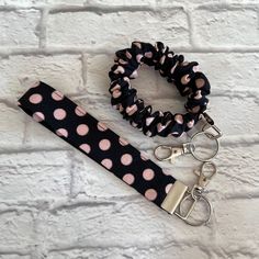 two black and pink polka dot lanyards with matching hair ties on a brick wall