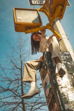 a woman leaning up against a street sign on the side of a pole with one foot in the air