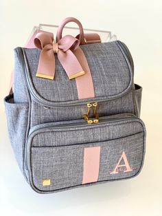 a gray and pink bag with a bow on the front, sitting on a white surface