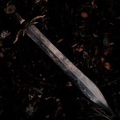 a knife is laying on the ground with leaves around it and some dead plants in the background