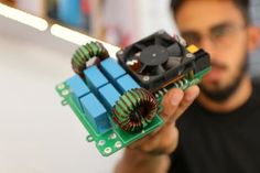 a man holding up an electronic device with many wires attached to the back of it