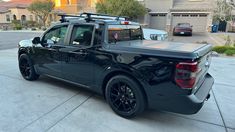 the back end of a black truck parked in front of a house on a driveway