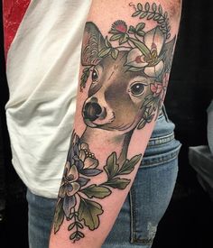 a woman's arm with a deer and flowers tattooed on the left side of her arm