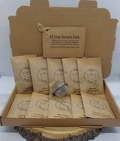 six tea sample packs in a cardboard box on a tree stump with tags around them