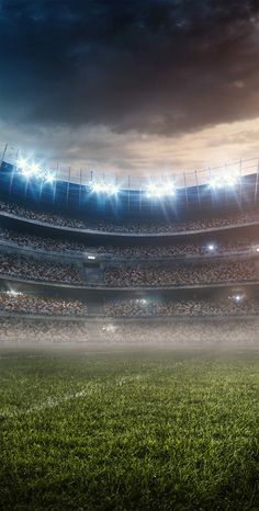 a soccer ball is on the field in front of an empty stadium at night time