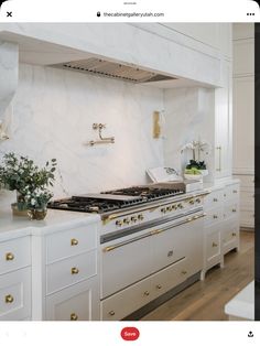 a kitchen with marble counter tops and gold trim on the oven hood, along with white cabinets