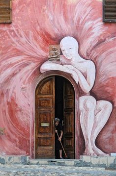 a person standing in front of a doorway with a painting on it's side