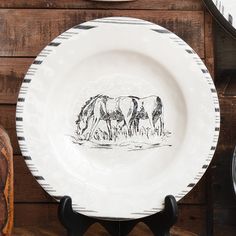 two plates with horses drawn on them are sitting on a wooden table next to other dishes