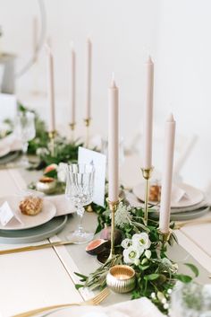 the table is set with candles, plates and napkins for an elegant dinner party