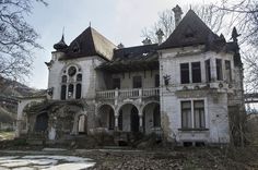 an old abandoned house with lots of windows and balconies on the front porch