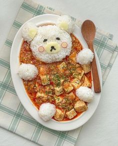 a white plate topped with rice and meat next to a teddy bear on top of it