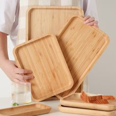 a person holding two bamboo trays with slices of bread on them and one half empty