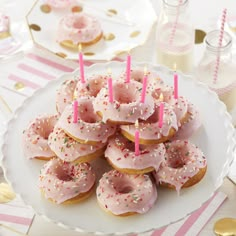 a white plate topped with donuts covered in pink frosting and sprinkles