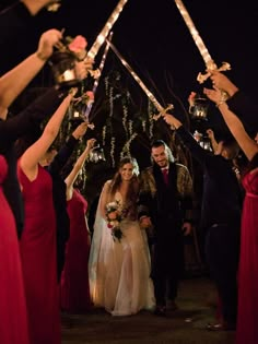 a bride and groom walking down the aisle with their hands in the air holding sparklers