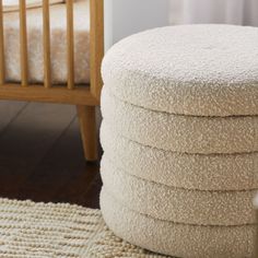 a stack of white towels sitting on top of a rug next to a crib