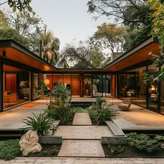 a modern house in the middle of a park with lots of trees and plants around it