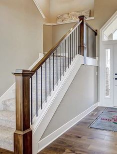 an entryway with stairs and rugs on the wooden floor next to white doors