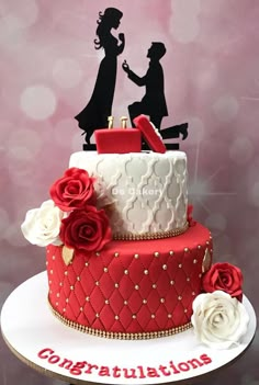 a red and white wedding cake with the silhouettes of bride and groom on top