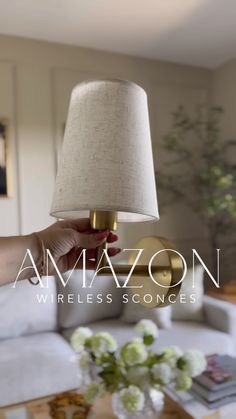 a person holding a lamp in their hand with the words amazon wireless sconces above it