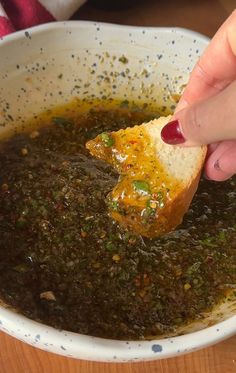 a person dipping something into a bowl of soup