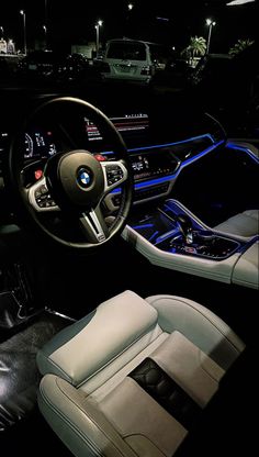 the interior of a car with leather seats and steering wheel, illuminated by blue lights