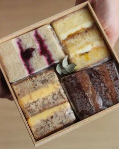 a person holding a box with different types of cakes in it