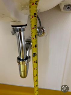 a measuring tape is hanging from the side of a wall next to a sink and faucet