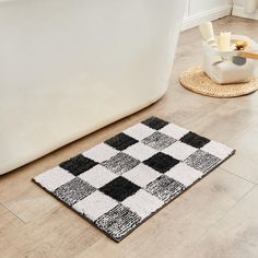 a black and white checkered rug on the floor next to a bathtub in a bathroom