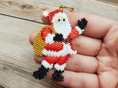 a hand holding a beaded keychain with a santa clause on it's face