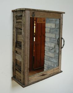 a mirror hanging on the side of a wall with a brick and wood frame around it