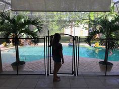 a woman standing in front of a pool looking out the glass door to another pool