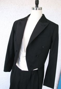 ABOUT THIS STYLE: A classic white tie suit straight out of the 1930s. This look features a formal tailcoat with silk-face grosgrain peak lapels, a pointed hemline, and curved tails. The outfit also features a white silk peak lapel vest and a custom formal pleated pant with a high waist. This style is famous for elongating the legs and creating the ultimate look of formal elegance. CUSTOM MADE: You can choose all of the details (tail shape, lapel shape, pant and cuff style) and fabrics (wools and Classic Formal Tuxedo With Flat Front, Classic Flat Front Tuxedo For Formal Occasions, Classic Flat Front Tuxedo, Classic Fitted Single Breasted Tuxedo, Classic Single Breasted Fitted Tuxedo, Classic Single-breasted Fitted Tuxedo, Classic Fitted Single-breasted Tuxedo, Elegant Tailored Full-length Blazer, Elegant Full-length Tailored Blazer