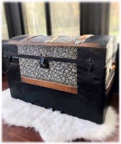 an old trunk sitting on top of a white furnishing rug in front of a window