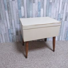 a small white box sitting on top of a wooden table in front of a wall